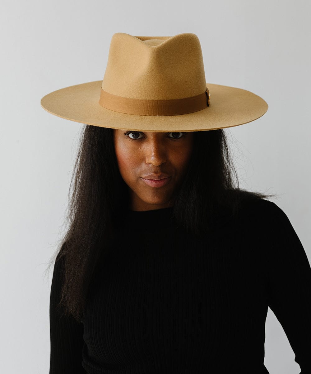 Woman wearing a honeycomb colored wide brim fedora hat with a band and a black t-shirt against a plain background #color_honeycomb