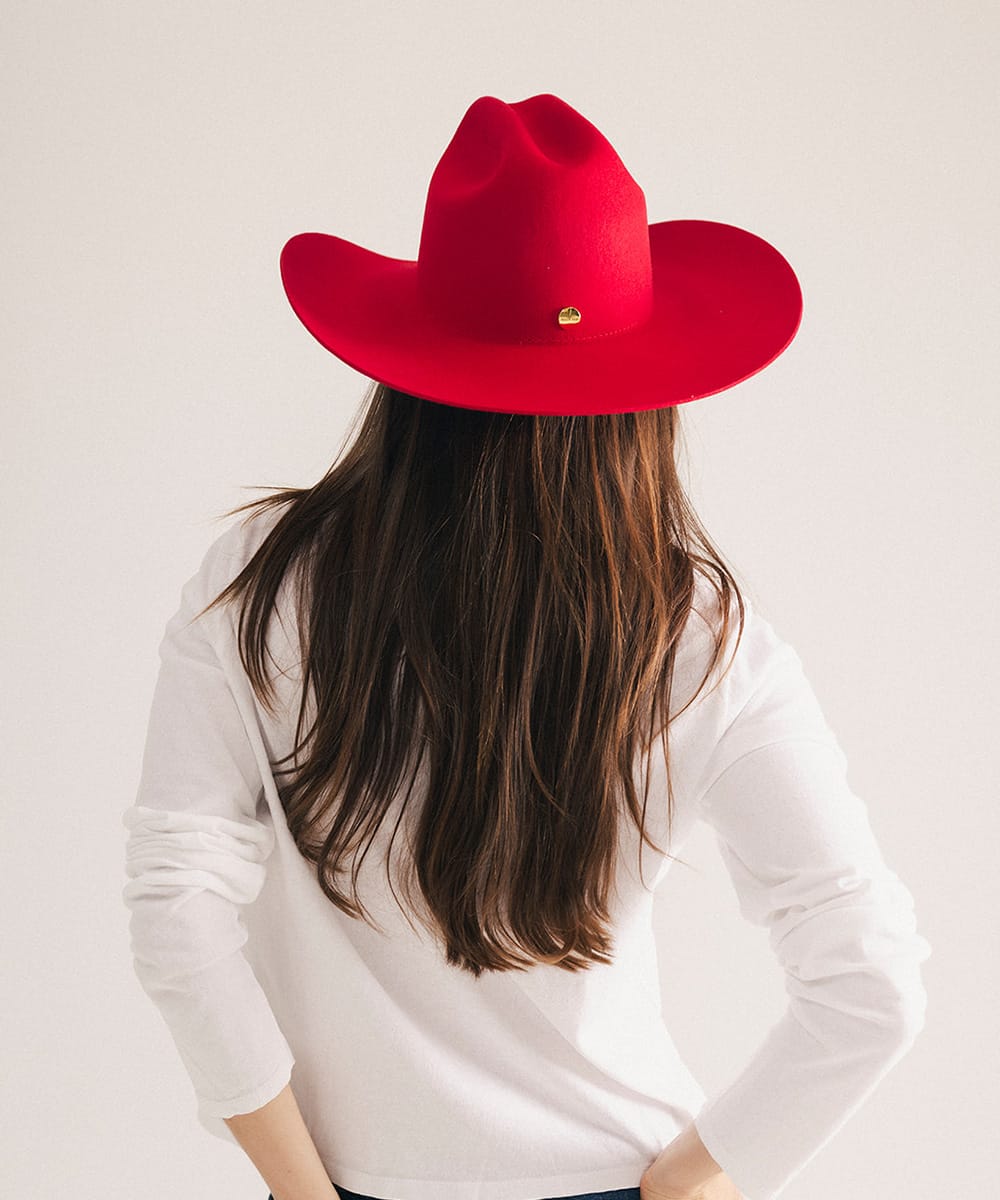 Woman wearing a red cowboy hat with a plain background #color_cherry red