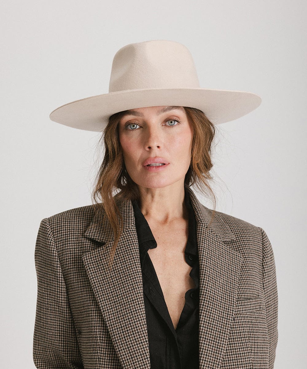 Woman wearing a cream fedora hat and a black shirt with a blazer against a plain background #color_cream