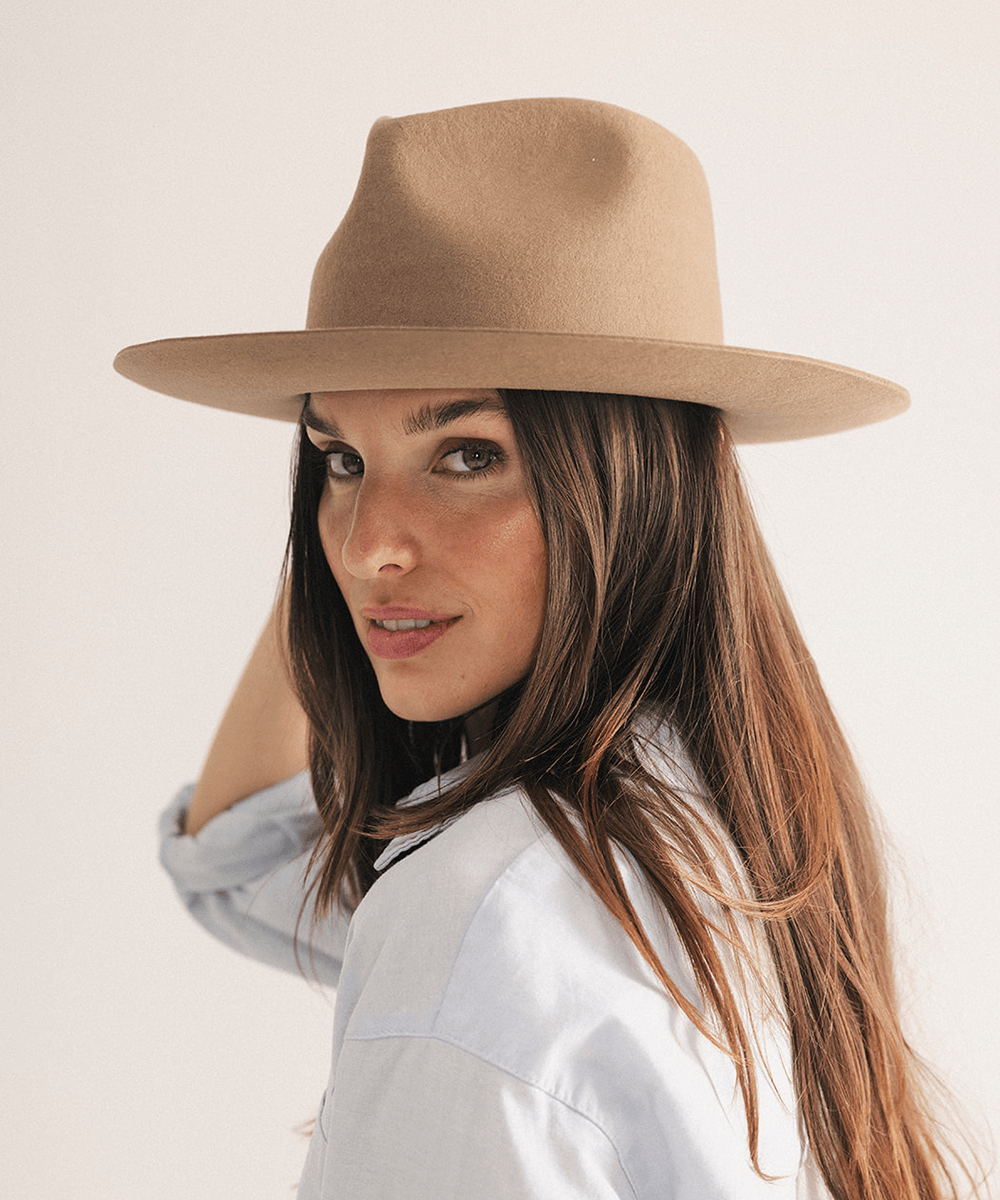 Woman wearing a brown fedora hat with a neutral background #color_brown