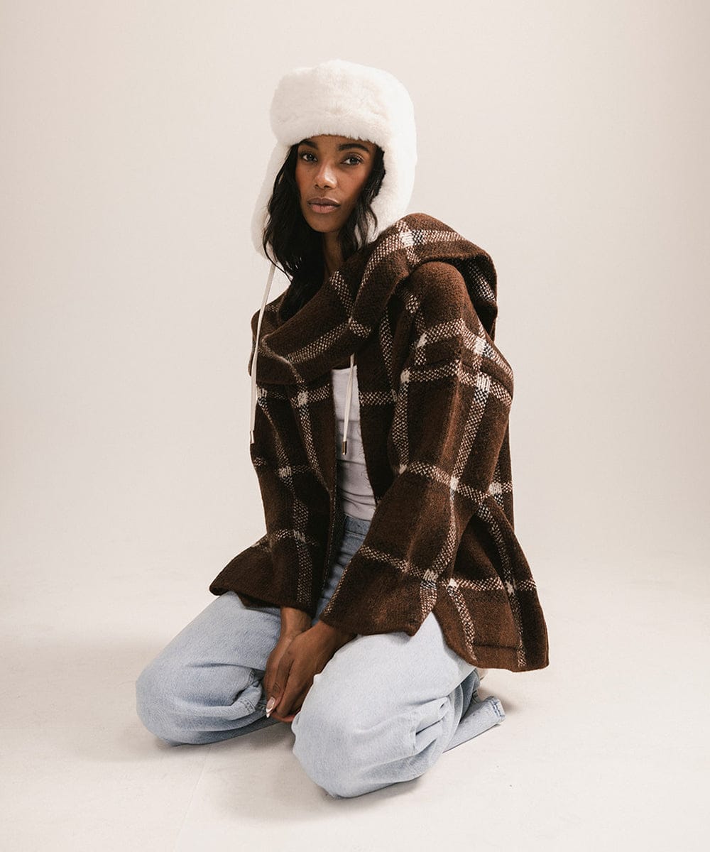 Person wearing a white hooded coat with a patterned brown garment underneath on a plain background #color_winter white