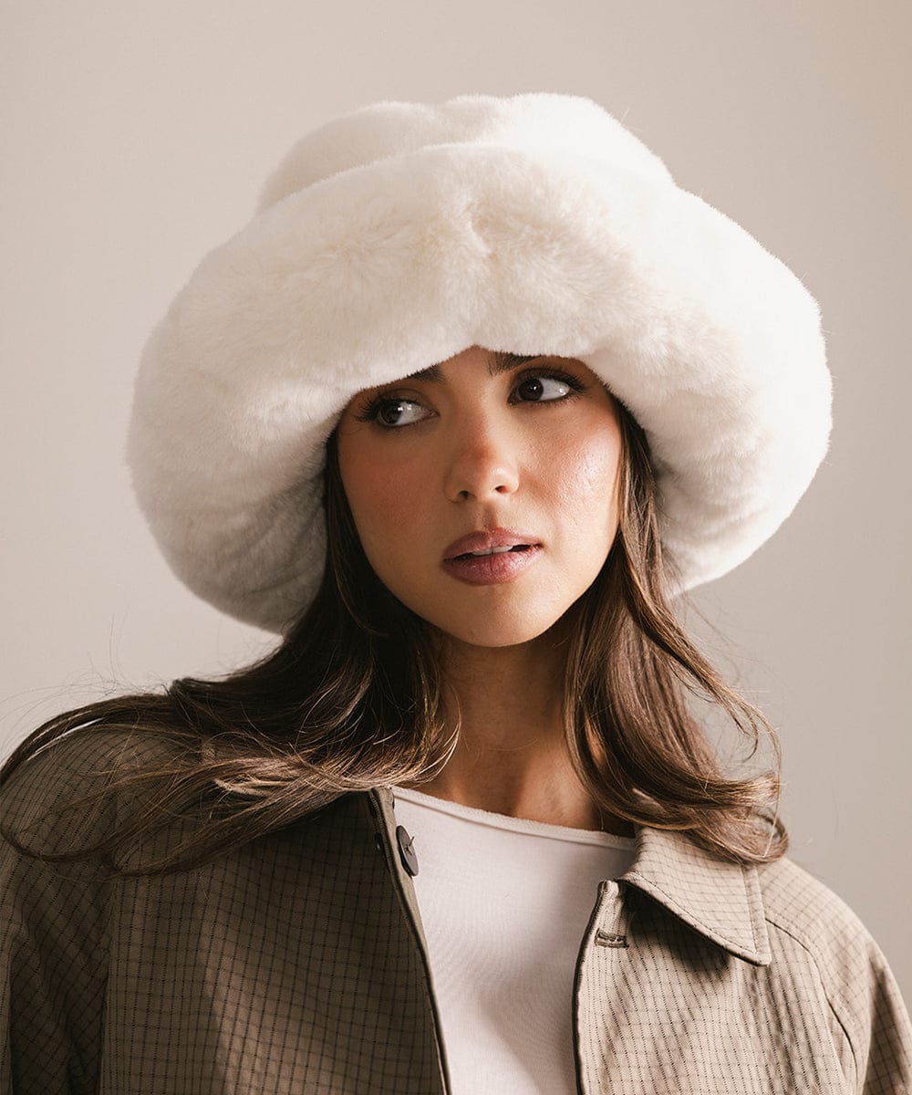 Woman wearing a white fur hat against a neutral background #color_winter white