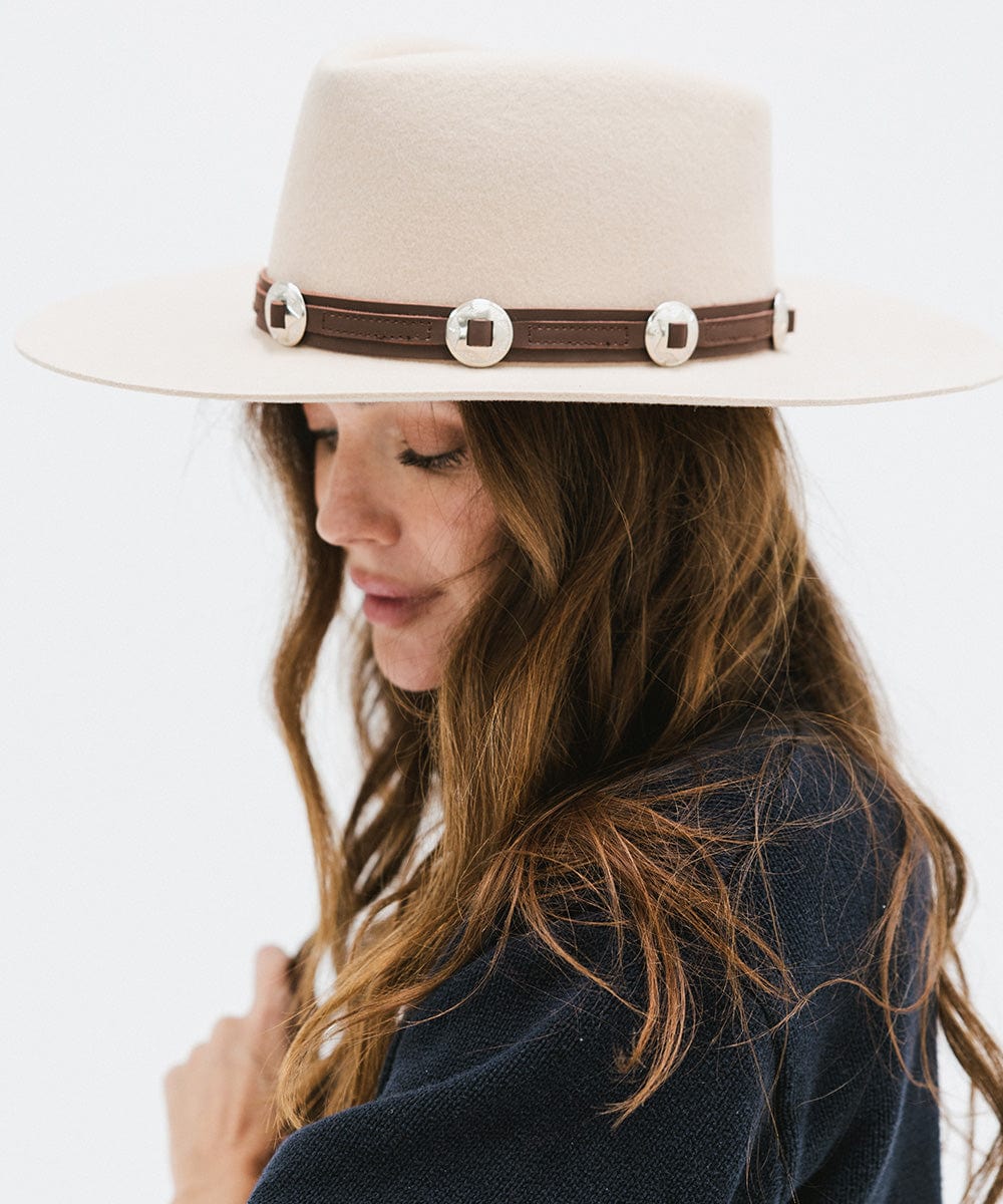 Woman wearing a white hat with a chocolate colored western style genuine leather hat band and a blue sweater, posing sideways against a plain background #color_chocolate
