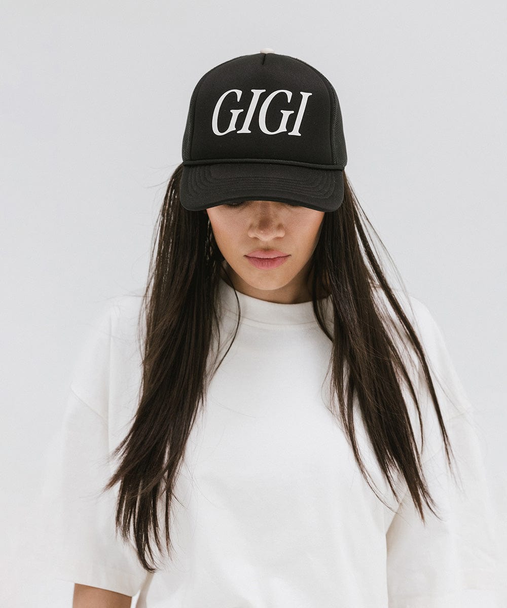Woman wearing a black cap with 'GIGI' text and a white t-shirt against a plain background #color_black