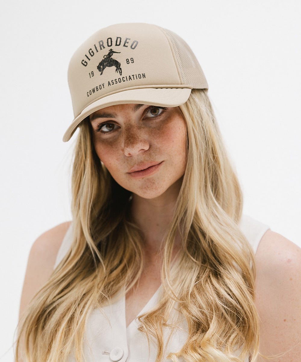 Woman wearing a tan cap with golden 'GIGIRODEO' text and logo against a plain background #color_tan