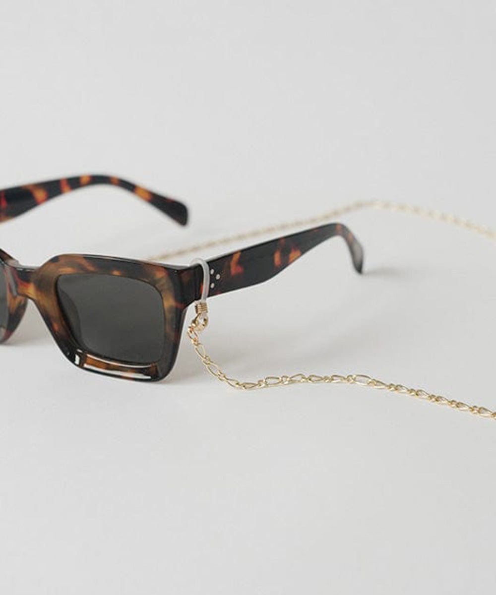 Sunglasses with tortoiseshell frame and gold chain strap on a plain background #color_gold