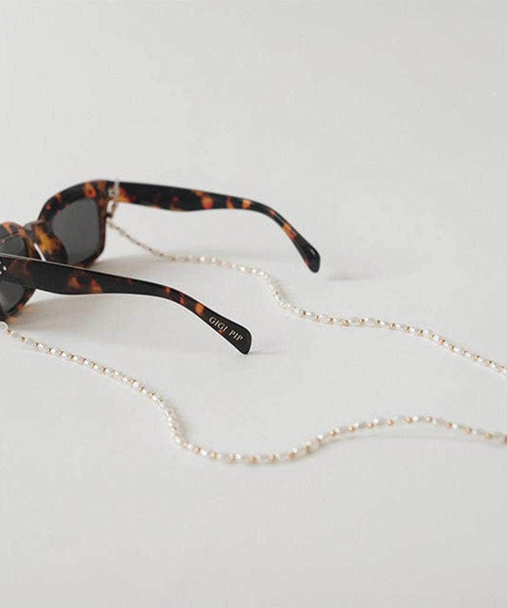 Sunglasses with a gold pearl chain strap on a plain background #color_gold