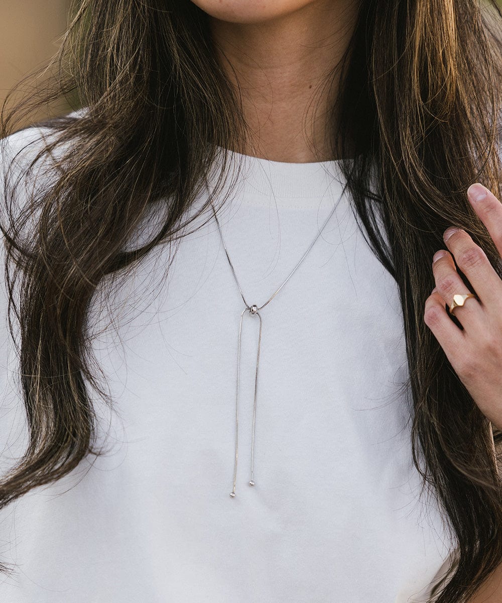 Woman wearing a white t-shirt and a silver chain bolo band around her neck #color_silver