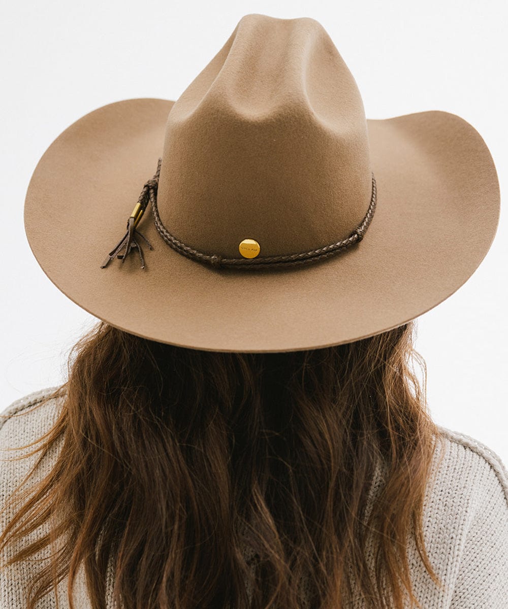 Person wearing tan cowboy hat with a brown lasso braided hat band against a plain background #color_brown