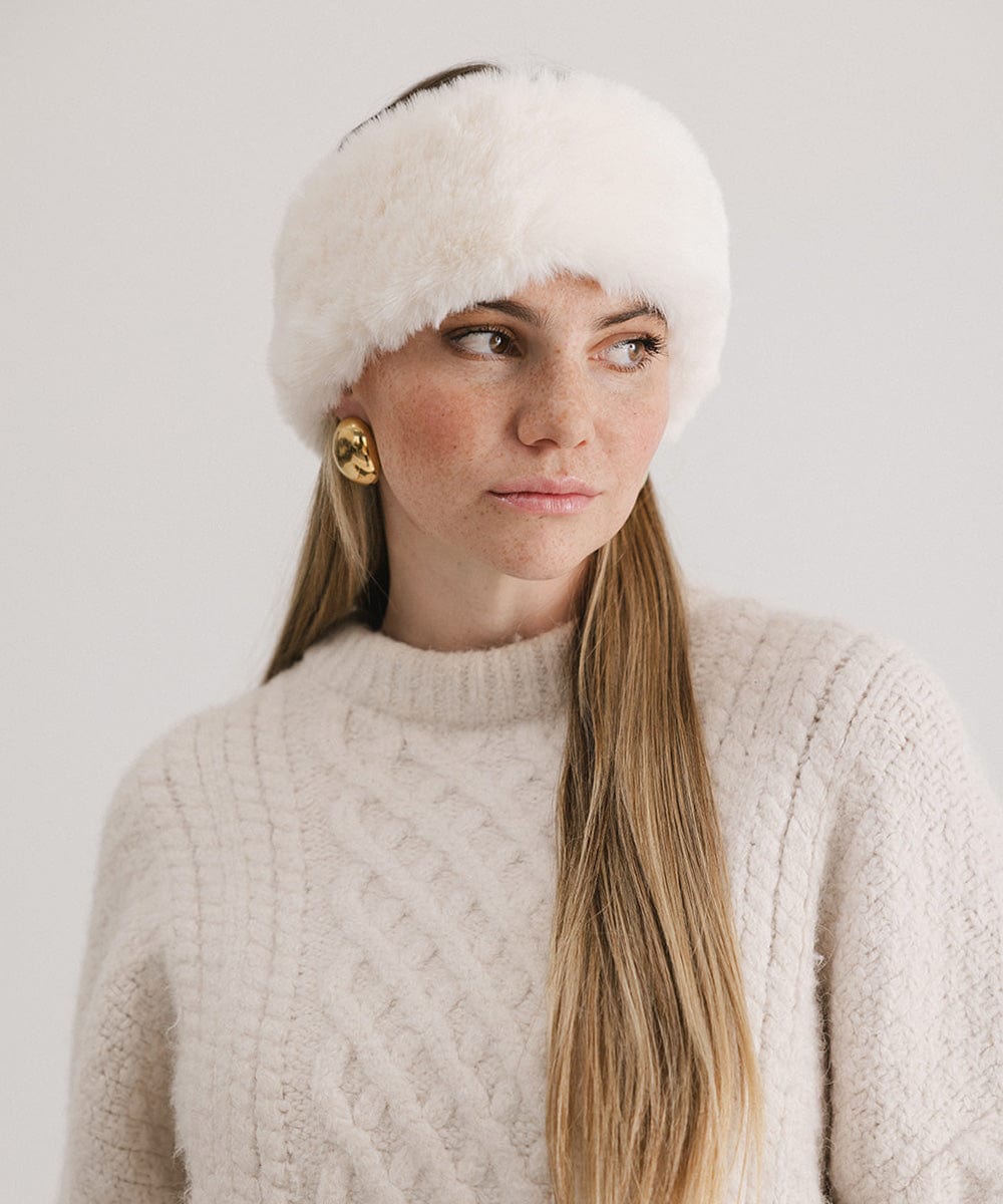 Woman wearing a winter white colored fur headband and a white sweater, posing against a plain background #color_winter white