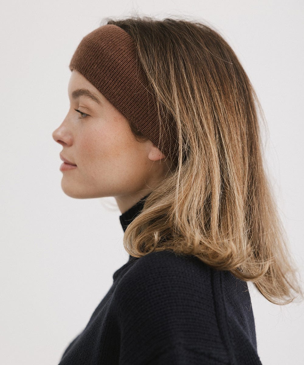 Woman wearing a chocolate colored headband and a black sweater, facing sideways against a plain background #color_chocolate