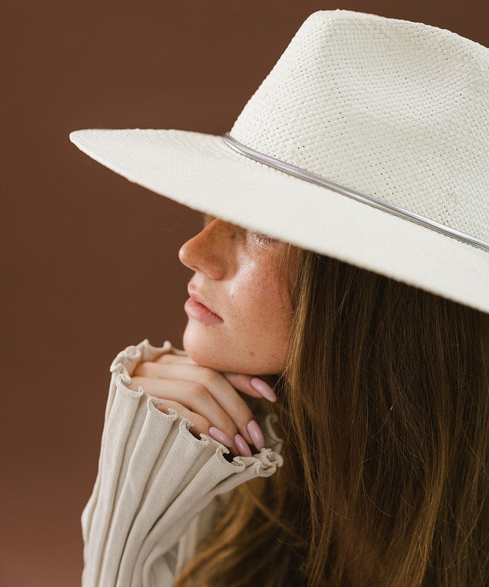 Woman wearing a white hat with a silver chain hat band facing sideways against a brown background #color_silver
