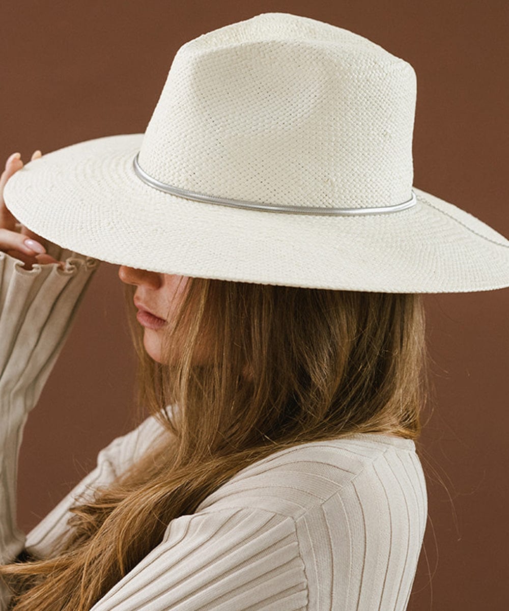 Woman wearing a white hat with a silver chain hat band and a white top, facing sideways against a brown background #color_silver