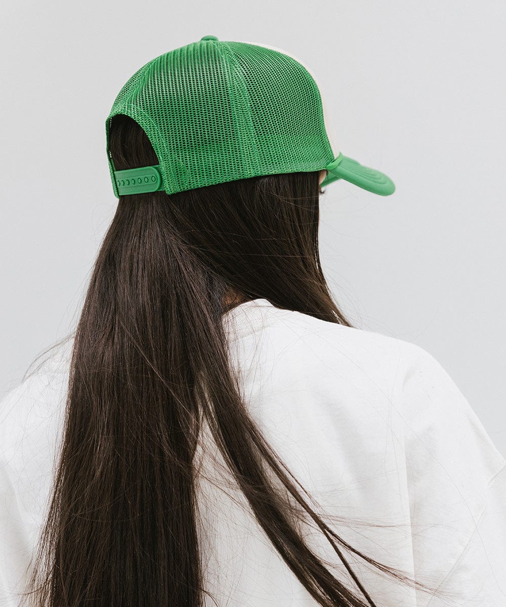 Woman with long hair wearing a cream and vintage green cap and a white t-shirt against a plain background #color_cream-vintage green