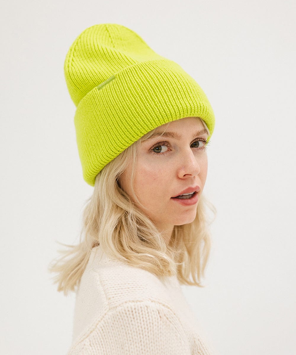 Woman wearing a lime colored oversized knit beanie against a plain background #color_limeade