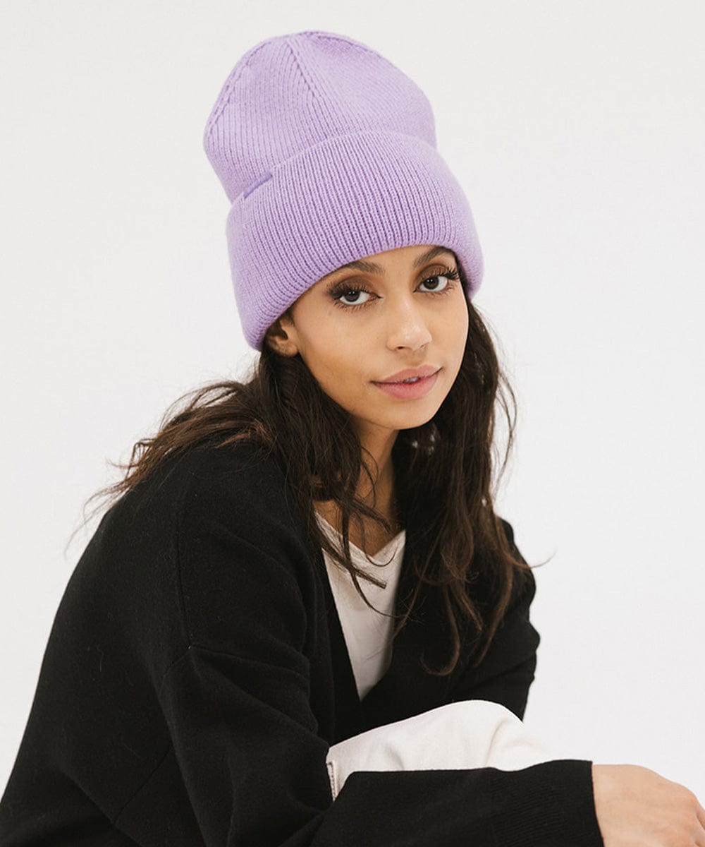 Woman wearing a lavender colored oversized knit beanie and a black shirt against a plain background #color_lavender