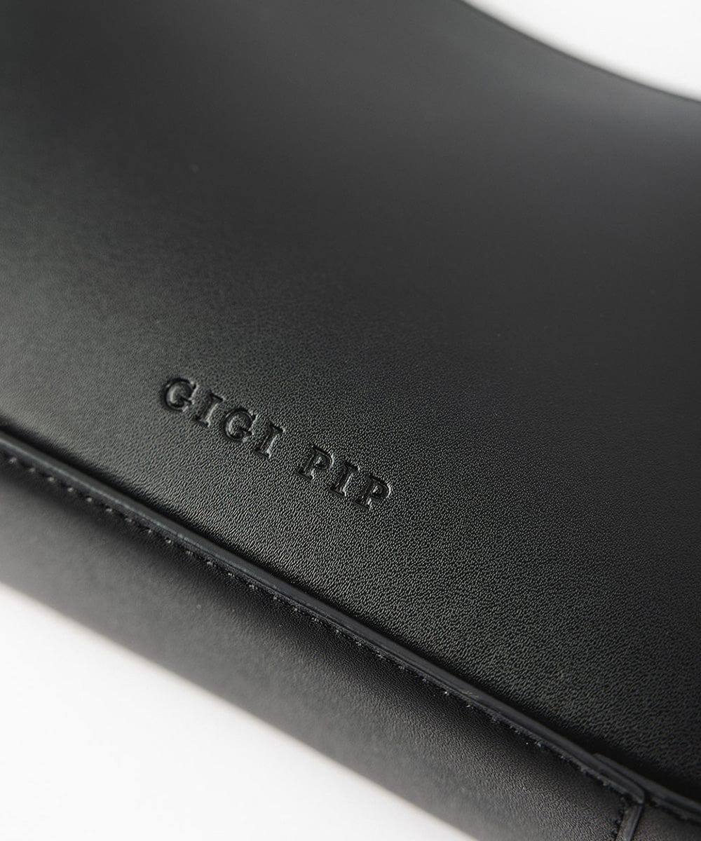 A black genuine leather handbag with the brand label on a plain background #color_black