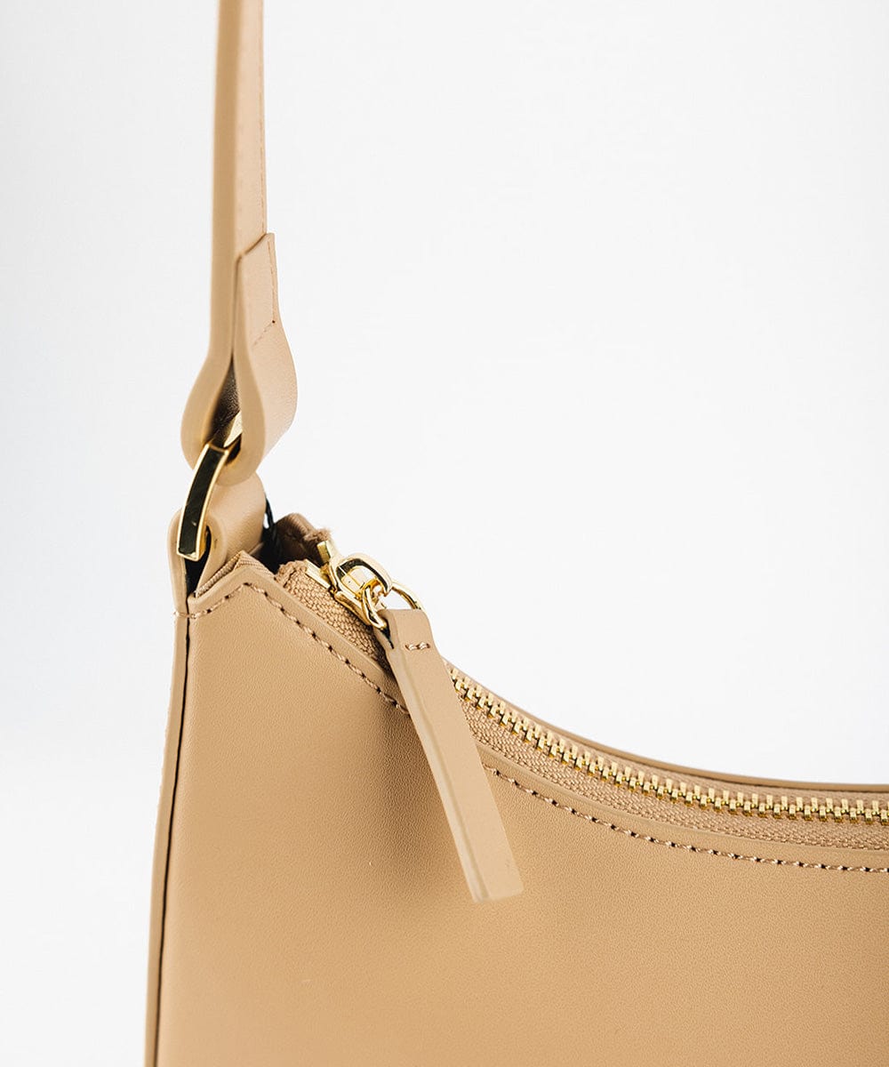 A tan genuine leather handbag with a golden zipper on a plain background #color_tan