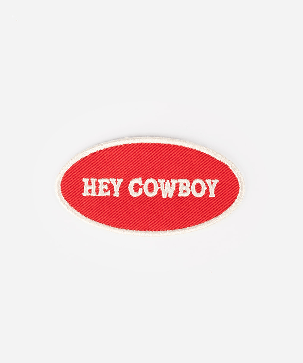 An oval embroidered patch with a red background and white border, featuring the text 'HEY COWBOY' in white capital letters, shown on a plain light gray background #color_red