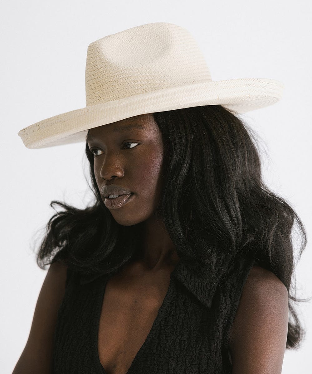 Woman wearing a natural colored pencil brim fedora hat and a black top against a plain background #color_natural