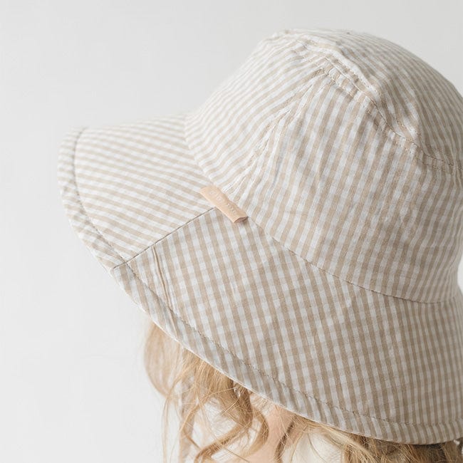 Close up image of someone wearing a latte colored bucket hat against a plain background #color_latte