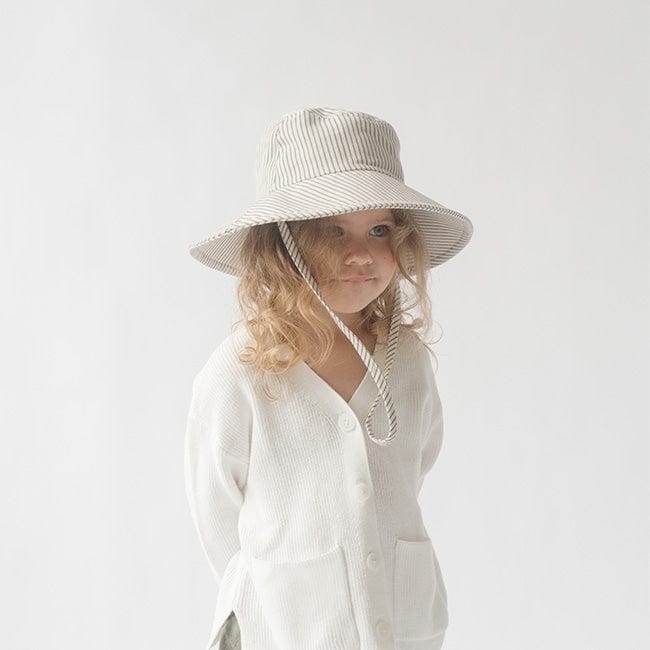 Young girl wearing a grey striped bucket hat and a white shirt against a plain background #color_grey