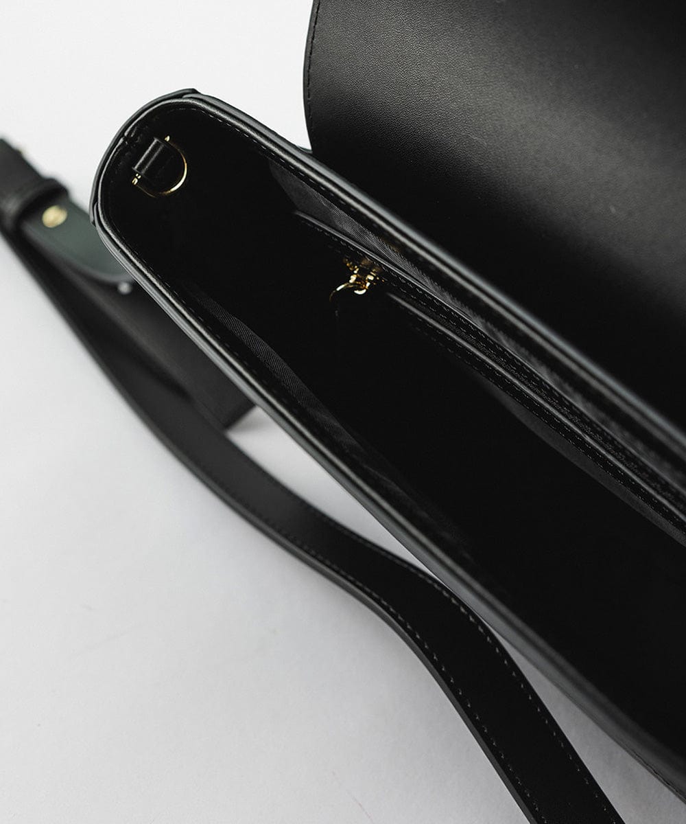 The top of a black Rhys Crossbody Genuine Leather Bag against a plain background #color_black