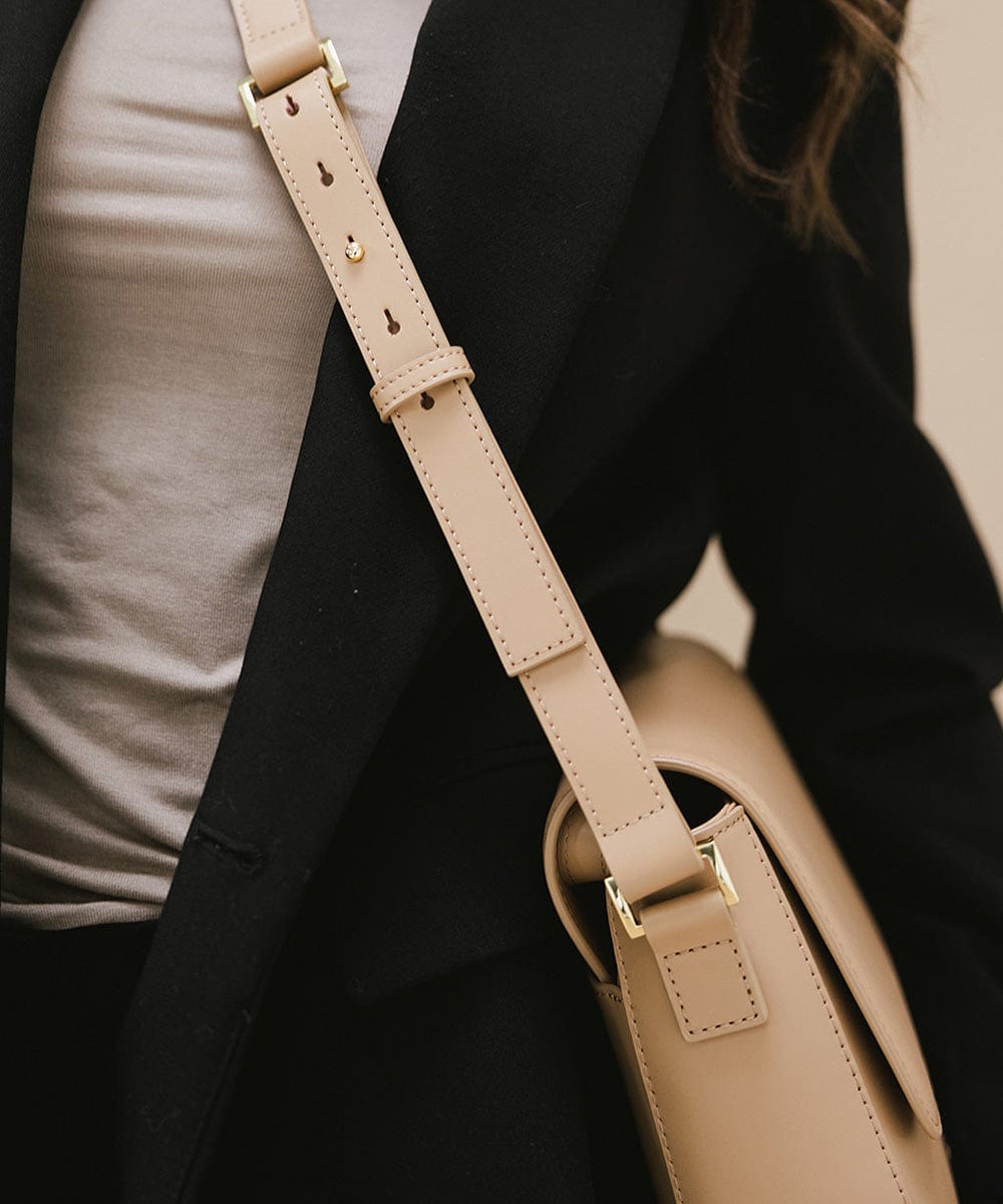 Person wearing a white t-shirt with a black blazer, carrying a tan Rhys Crossbody Genuine Leather Bag #color_tan