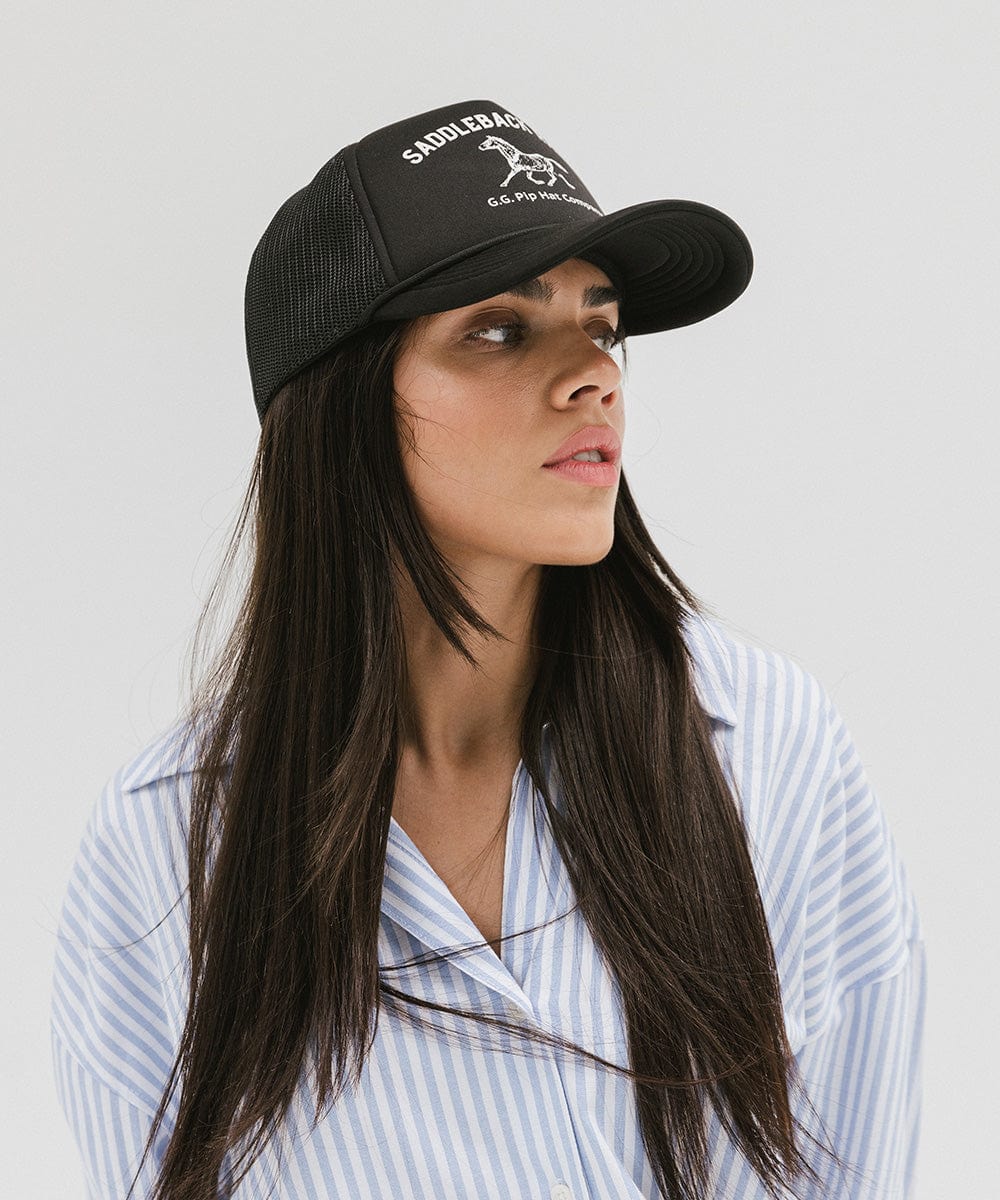 Woman wearing a black cap with 'Saddleback Ranch' text and logo and a light colored shirt, looking sideways against a plain background #color_black