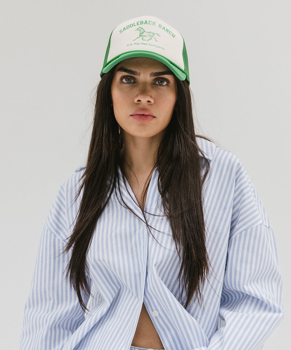 Woman wearing a cream and vintage green cap with 'Saddleback Ranch' text and logo, and a shirt against a plain background #color_cream - vintage green
