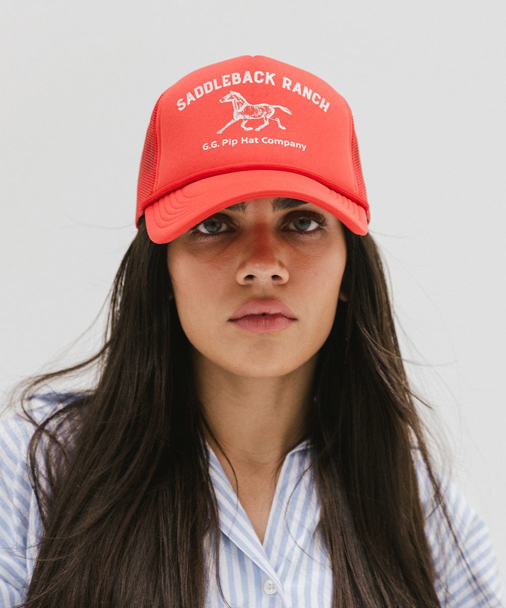 Woman wearing a vintage red colored cap with 'Saddleback Ranch' text and logo, and a light colored shirt against a plain background #color_vintage red