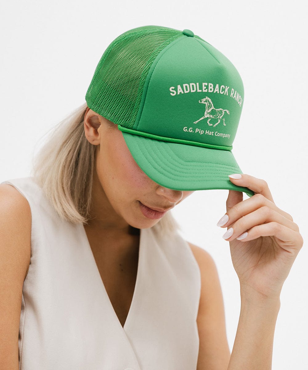 Woman wearing a vintage green colored cap with 'Saddleback Ranch' text and logo, and a white top, posing against a plain background #color_vintage green