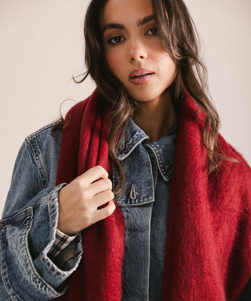 Woman wearing a red scarf and denim jacket against a plain background #color_burgundy