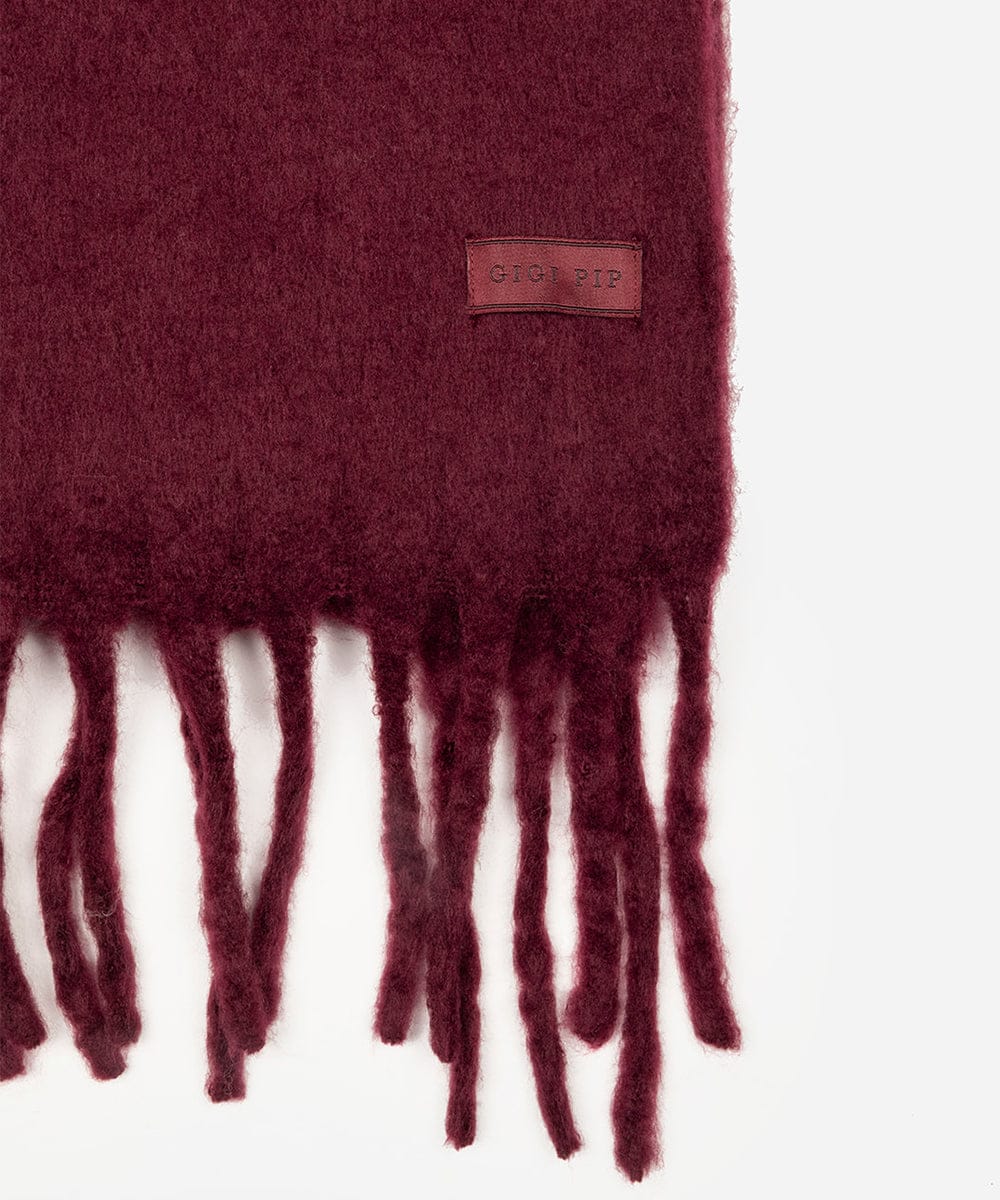 Maroon scarf with fringes and a brand label on a white background #color_merlot
