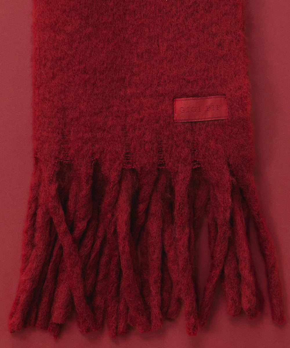 A burgundy oversized knit scarf with fringes against a red background #color_burgundy