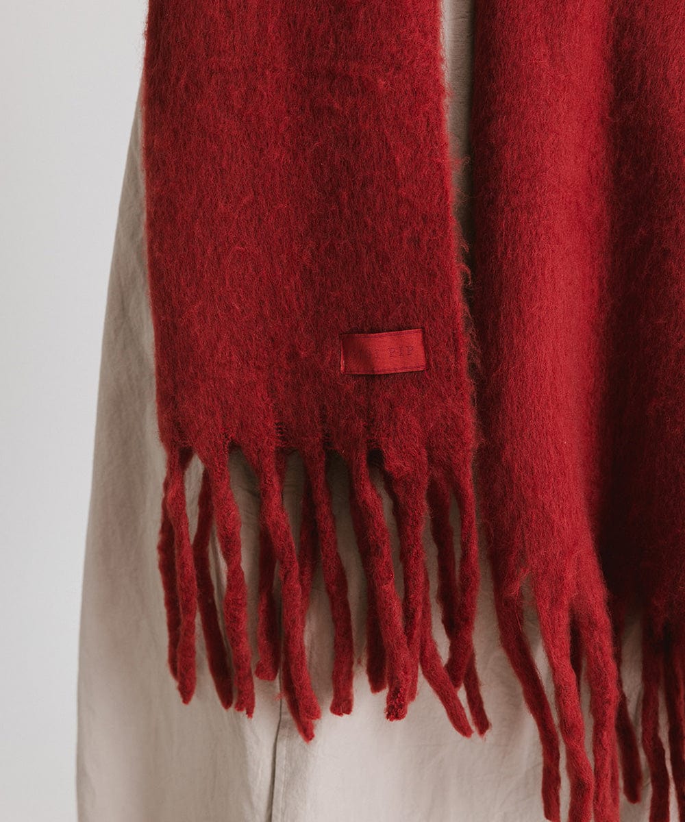 A burgundy knit scarf with fringes, against a plain background #color_burgundy