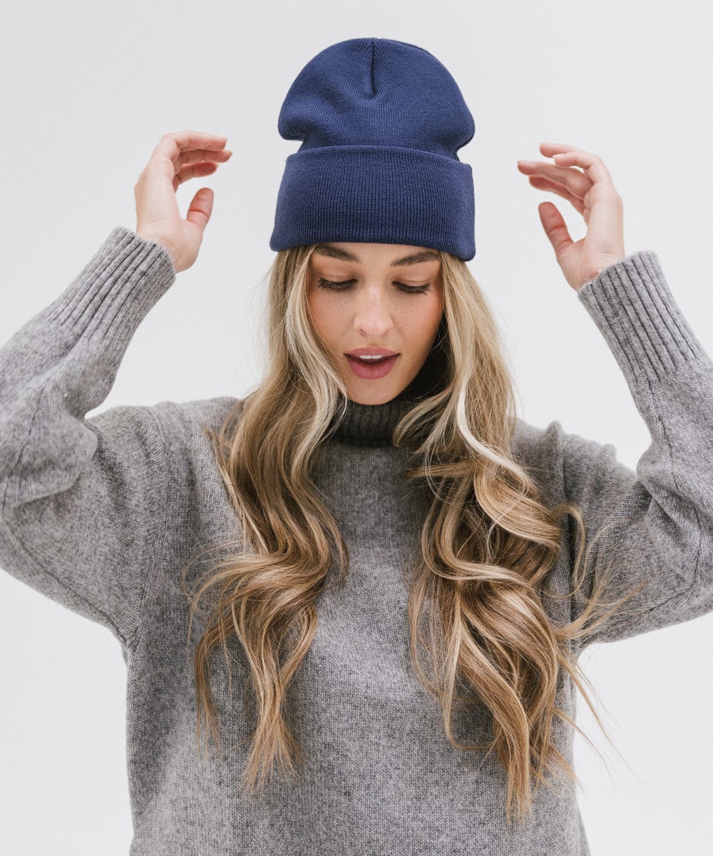 Woman wearing a navy beanie and a grey sweater, posing against a plain background #color_navy