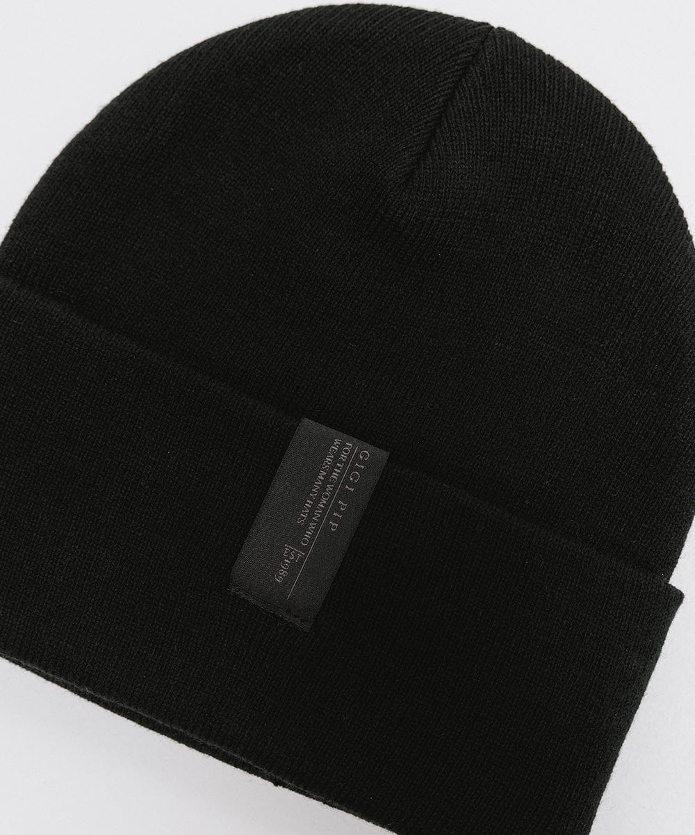 A black beanie with the brand label on a plain background #color_black