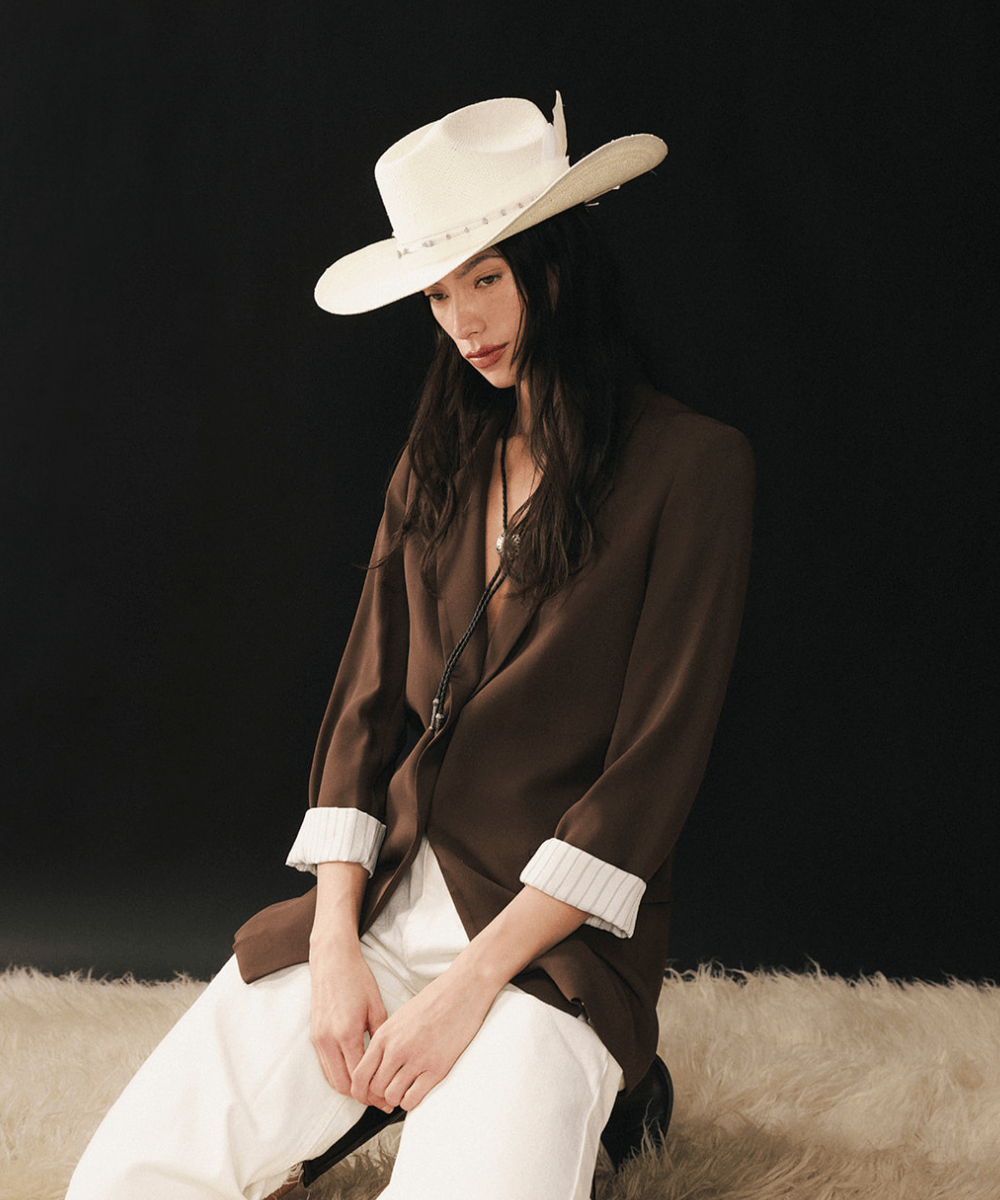 White colored straw cowboy hat on a woman with a black background #color_natural white
