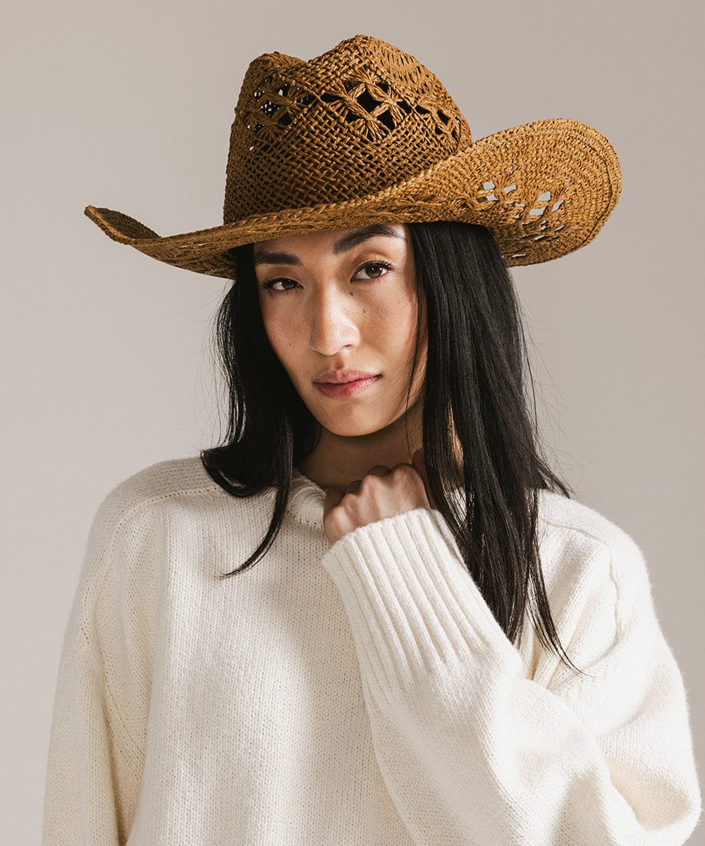 Woman wearing a honey colored paper rope straw cowboy hat and a white sweatshirt against a plain background #color_honey