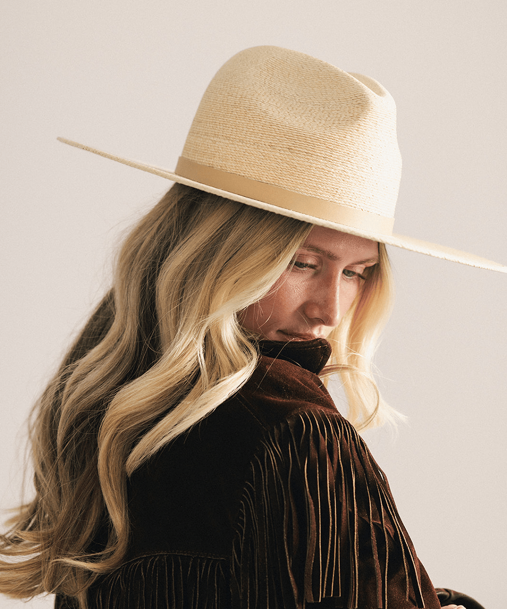 Woman wearing a natural colored Blake Wide Brim Fedora Hat with a flat wide brim and a tonal genuine leather band, displayed against a plain background. #color_natural