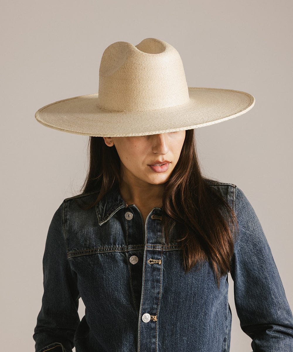 Woman wearing a natural colored western wide brim straw hat and a denim jacket against a plain background #color_natural