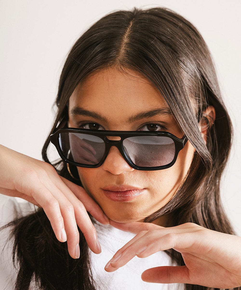 Woman wearing black sunglasses and against a plain background #color_black