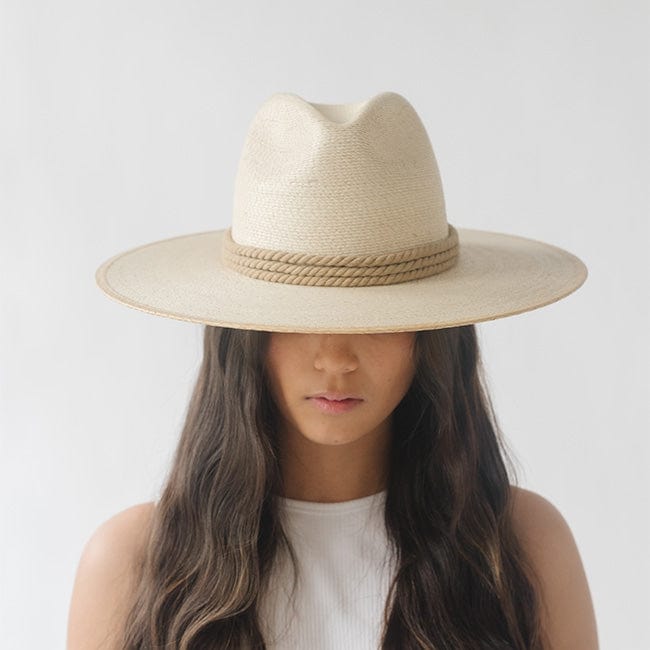 Woman wearing a beige hat with a dusty blue colored thick rope hat band and a white top against a plain background #color_dusty blue