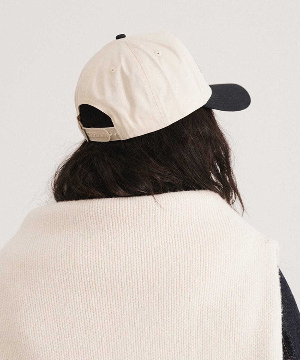 Woman wearing a Navy Trucker hat and a white sweater against a plain background #color_navy