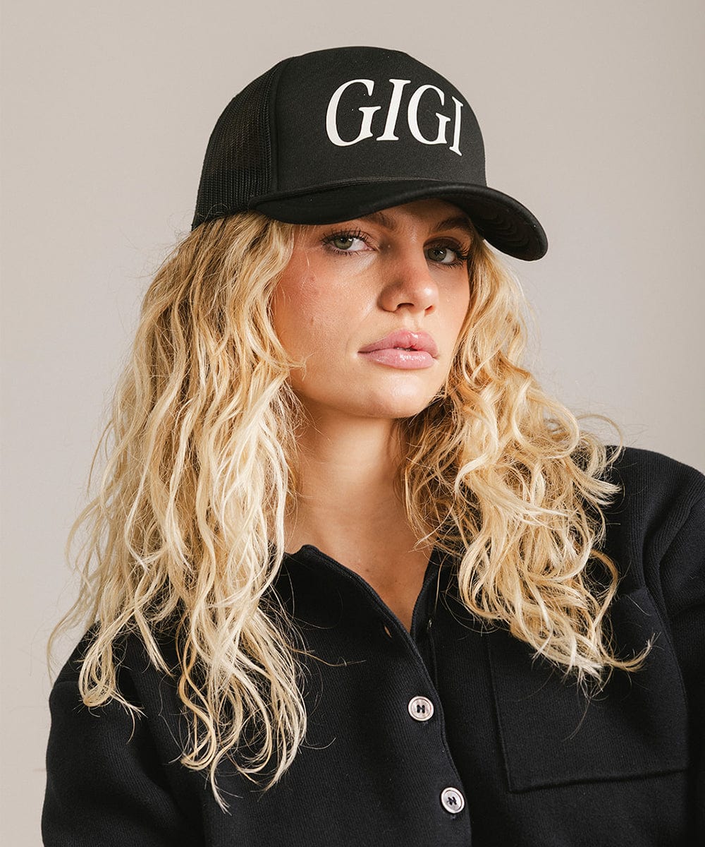 Woman wearing a black cap with 'GIGI' text and a black shirt against a plain background #color_black