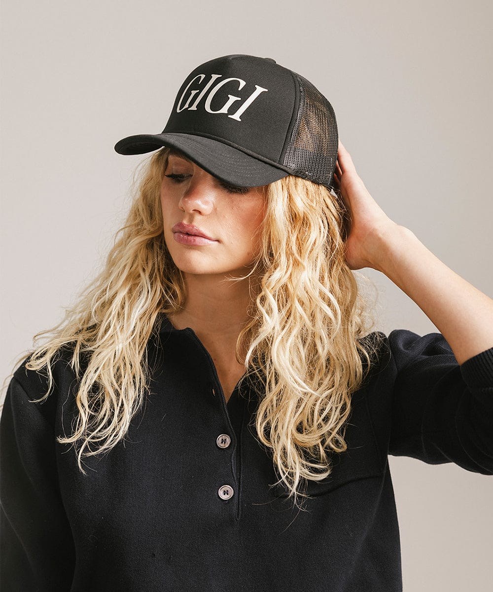 Woman wearing a black cap with 'GIGI' text and a black shirt, posing against a plain background #color_black
