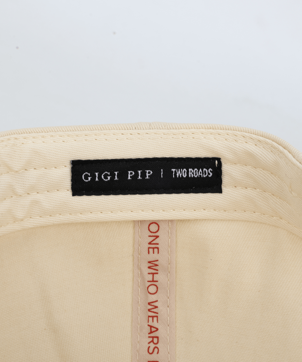 Embroidery inside a hat that says 'GIGI PIP | TWO ROADS' in a white background #color_cream - rust red