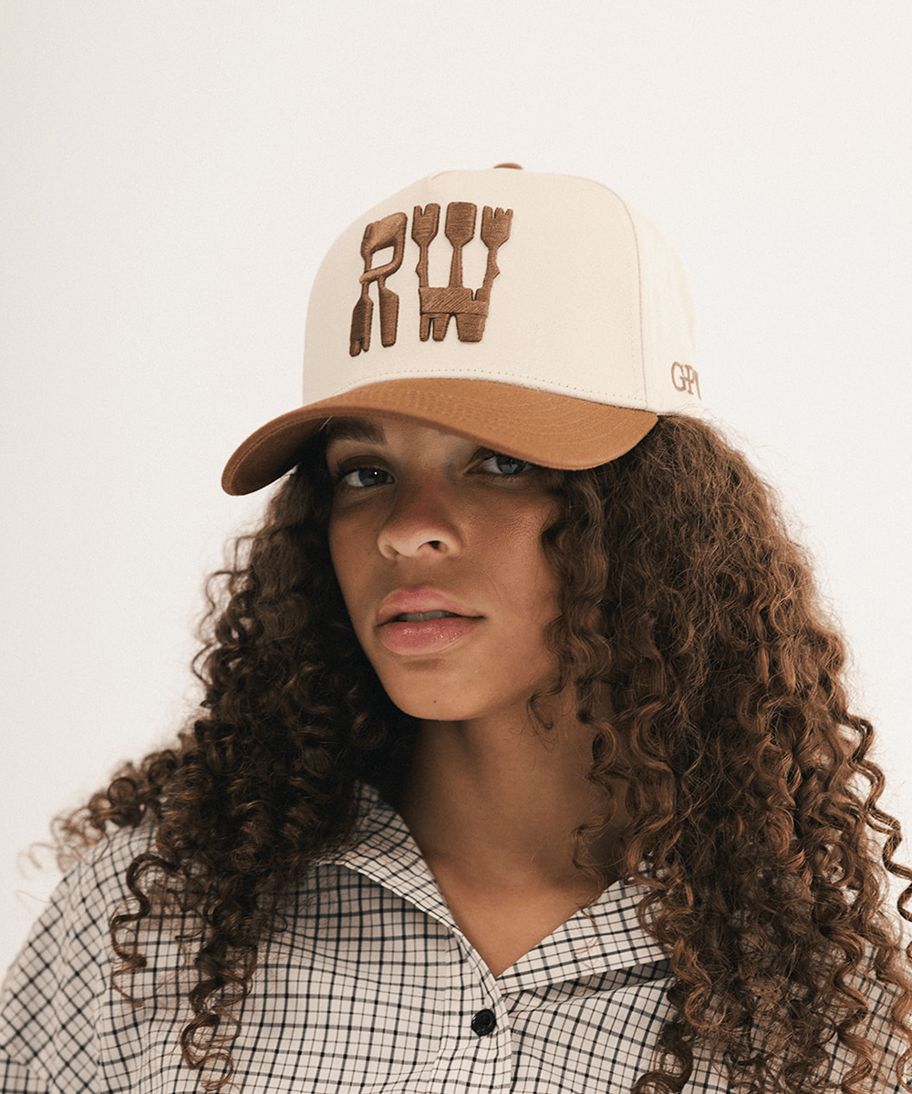 Woman wearing a baseball cap and plaid shirt on a white background #color_cream - tan