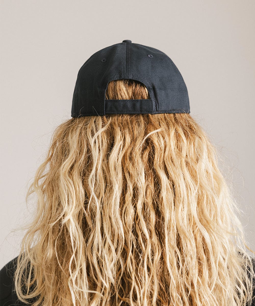 Woman with long hair wearing a navy cap against a plain background #color_navy